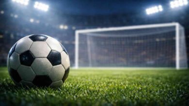 Palla da calcio in primo piano e sullo sfondo la porta vuota da calcio